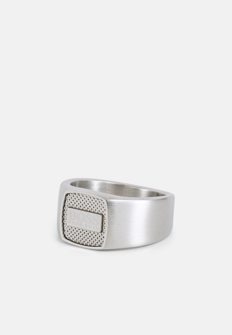 Bague homme ton argent avec face carrée texturée comportant la gravure "BOSS HUGO BOSS", anneau poli et design moderne.