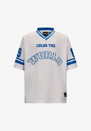 Witte trui met blauwe tekst "KLEUR DE WERELD", korte mouwen, V-hals en genummerde accenten op de linkermouw.