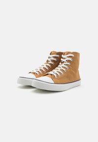 Høye sneakers i brunt lerret med hvite snørebånd, gummitåhette og hvit yttersåle. Har en strukturert design og kontrasterende mørkeblå sømmer.
