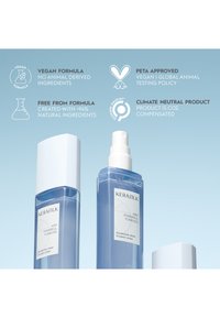 Zwei blaue Kérastase Volumenspray-Flaschen mit weißen Verschlüssen, die vegane, natürliche, von PETA zugelassene und klimaneutrale Produkteigenschaften hervorheben.