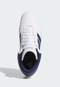 Weißer Adidas Sneaker mit marineblauen Streifen und Kragen, weißen Schnürsenkeln und perforierter Zehenkappe, von oben auf hellem Hintergrund betrachtet.