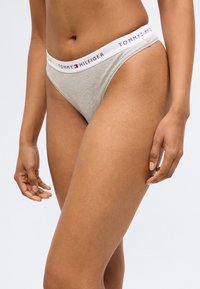 Tommy Hilfiger női tangapaplan világosszürke színben, fehér elasztikus derékpánttal, márkás logós felirattal. Sima szövet textúra.