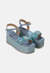 Des sandales en wedge bleu ciel présentent une plateforme tissée, ornée de embellissements en turquoise et en cristal sur les sangles et d'une semelle intérieure métallique.