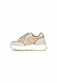Sneaker avec une combinaison de satin rose doux et de daim beige, présentant des accents verts, des lacets ronds, un détail de logo et une épaisse semelle blanche.