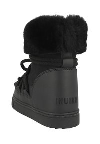 Botas de tobillo de ante y cuero negro con un suave puño de piel negra, detalles de cordones y una suela de goma texturizada. "INUIKII" grabado en el tacón.