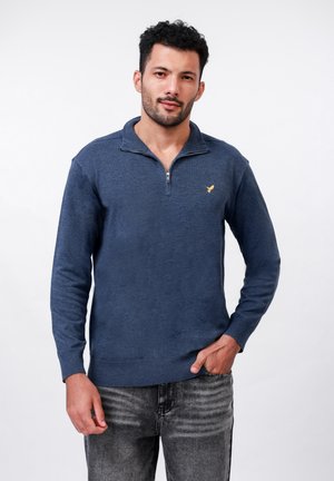 Marineblauwe zip-neck trui van zachte stof, met lange mouwen, ribgebreide manchetten en zoom, en een klein gouden logo op de borst.