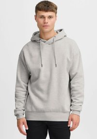 Haut à capuche gris clair avec cordons de serrage, poche kangourou et poignets côtelés. Tissu doux avec une coupe décontractée. Design simple, sans motifs.
