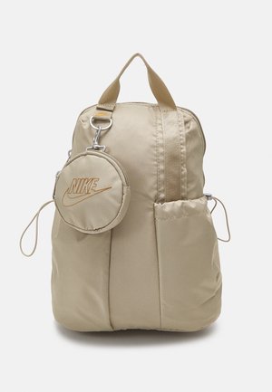 Beige Nike-rygsæk med top-håndtag, en rund aftagelig pung med broderet logo, sidelommer og lynlåslukning.