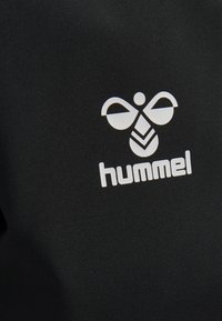 Schwarzer Stoff mit einem auffälligen weißen Logo einer stilisierten Biene und dem Wort "hummel", das zentral auf dem Material platziert ist.