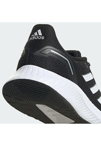 Chaussure de running Adidas noire avec semelle blanche et trois bandes blanches latérales, vue en contre-plongée arrière montrant la semelle texturée et le logo au talon.