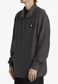 Gray fleece pullover with a quarter-zip collar, textured surface, front pocket, and a small triangular logo on the chest.