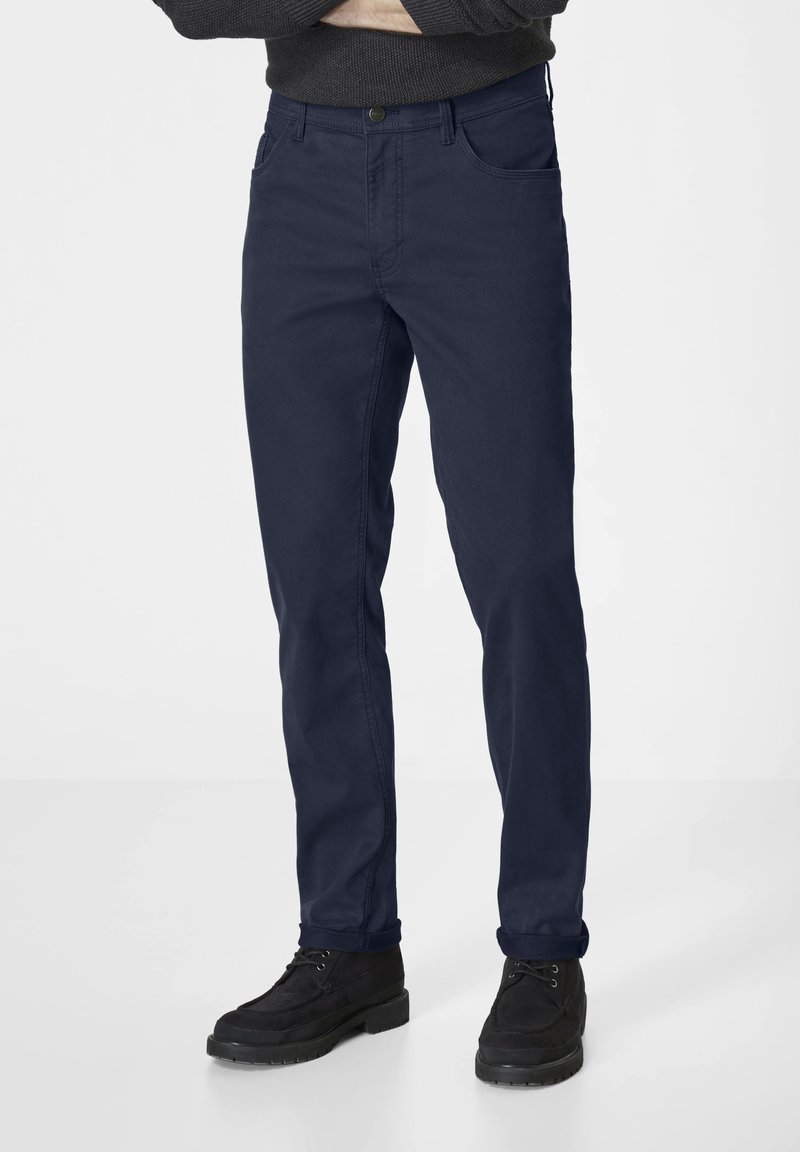 Navy-blue cotton chinos with a straight fit, featuring belt loops, front pockets, and a button closure. Worn with black ankle boots.