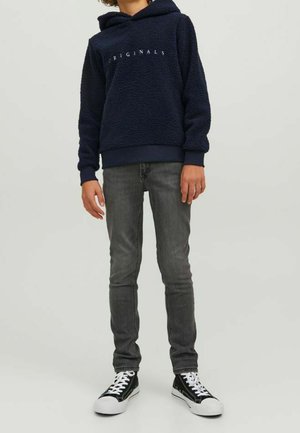 Laivaston fleece-huppari, jossa on "ORIGINALS"-teksti, yhdistetty hoikkamallisiin harmaisiin farkkuihin ja mustavalkoisiin lenkkareihin. Pehmeä pinta ja rento istuvuus.