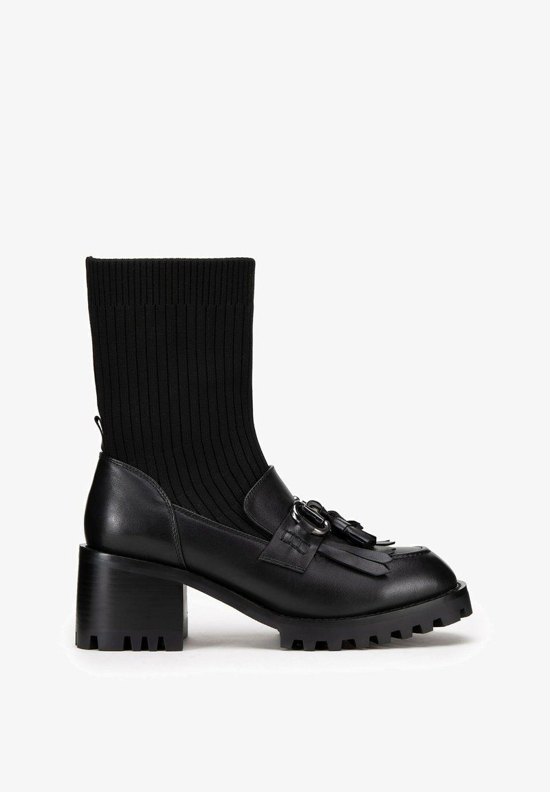Czarne botki za kostkę z prążkowanym, skarpetowym cholewką, skórzaną konstrukcją, dekoracyjnymi frędzlami oraz masywnym, gumowym obcasem z teksturowaną podeszwą.