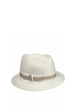 White woven fedora hat with a beige and cream ribbon band and a small round metallic logo tag on the side.