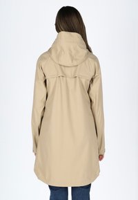 Beige veske regnjakke med hette, lange ermer og rett snitt, med bakstykke og trykknapper på mansjettene.