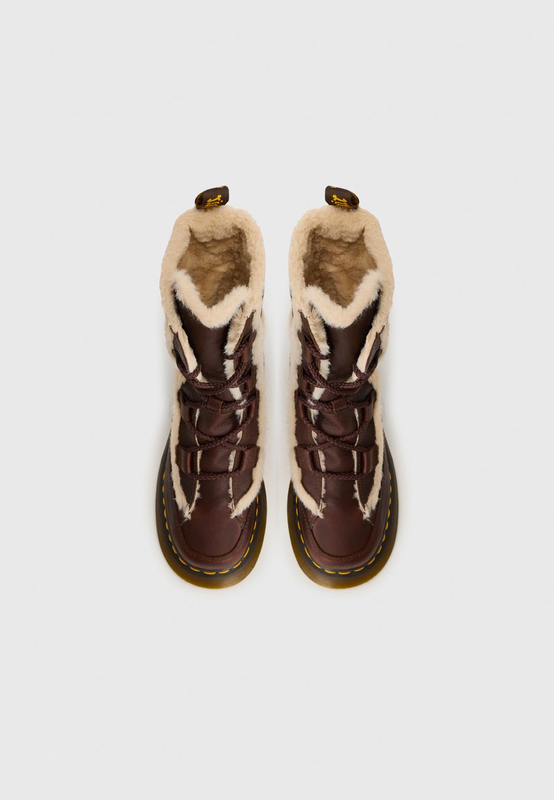 Bruna läderstövlar med en fluffig beigefärgad foder, med snörningsdesign, gula sömmar och rund sula. Toppvy.
