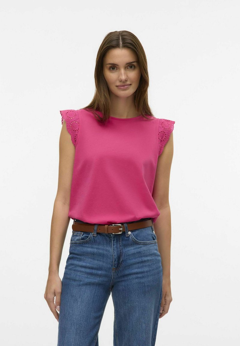 Fuchsia T-shirt met korte mouwen en kantafwerking op de schouders, gecombineerd met blauwe high-waisted jeans en een bruine riem, wat zorgt voor een casual outfit.