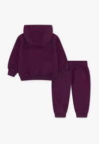 Violetinės gobtuvinės trikotažinės palaidinės ir atitinkančios kelnes, pagamintos iš švelnios medvilnės, su įpjautais rankogaliais ir juosmens juosta. Paprastas, funkcinis dizainas.