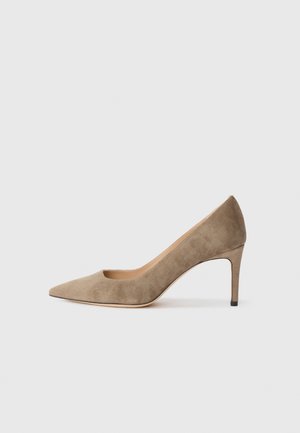 Escarpin en suédine beige à talons hauts avec un bout pointu, un décolleté bas et un talon stiletto fin. Texture lisse, design épuré.