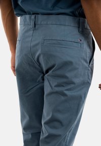 Pantalones azul claro hechos de un material suave y tejido. Presentan un bolsillo trasero y un pequeño logo en la parte trasera de la cinturilla.