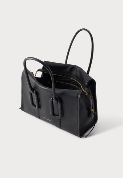 Sac à main en cuir noir avec deux poignées arrondies et une fermeture éclair dorée partiellement ouverte sur un fond uni clair.