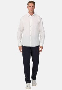 Witte lange mouw shirt met een button-down kraag, gecombineerd met marineblauwe broek en witte sneakers. Gladde stoftextuur, op maat gemaakte pasvorm.