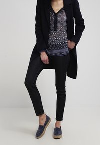 Granatowy długo płaszcz na wzorzystą niebieską bluzkę, czarne rurki i granatowe espadryle o teksturowanym wykończeniu i jutowej podeszwie.