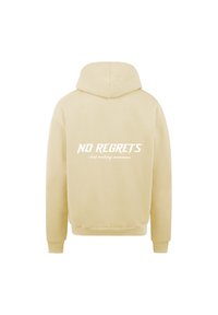Felpa beige con finitura testurizzata. Presenta testo stampato bianco sul retro: "NESSUN RIMPIANTO" e "Solo ricordi da creare". Stile felpa con tasca.