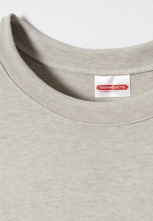 T-shirt grigio a manica corta con un texture liscia. L'etichetta recita "THERMOLACTYL di DAMART." Il colletto presenta un dettaglio di cucitura rinforzato.