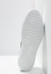 Sneakers z teksturowaną białą gumową podeszwą. Górna część wykonana z brązowego zamszu ma prosty, praktyczny design bez widocznych akcentów.