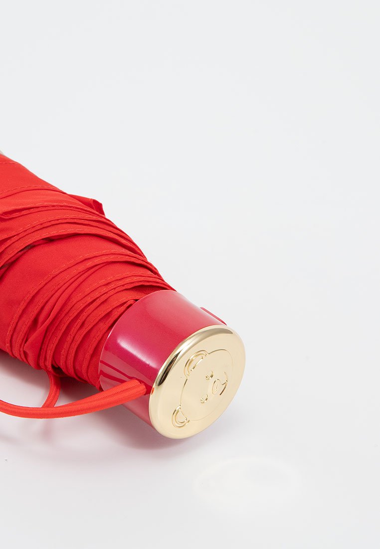 Roter zusammenklappbarer Regenschirm mit einem glänzenden pinkfarbenen Griff. Verfügt über eine goldene runde Kappe mit einem Bärenmotiv. Einschließlich eines passenden roten Tragebands.