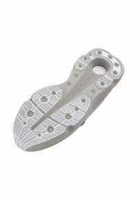 Semelle de chaussure avec une base en caoutchouc gris et un motif blanc, incluant des grips circulaires et des lignes verticales pour l'adhérence.