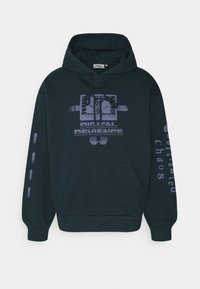 Černá mikina s kapucí vyrobená z bavlny, s přední kapsou, šňůrkami na stahování a grafickými potisky na přední straně a na rukávu. Obsahuje text "Digital Deviance".