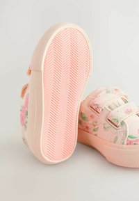 Rosa blommiga sneakers med två kardborreband, texturerad gummisole och mönstrad tyg med rosor och prästkragar på ovandelen.