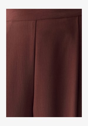 Donkerbruine stof met een verticale naad en plooidetail, die een gladde textuur en subtiele schaduw tonen.