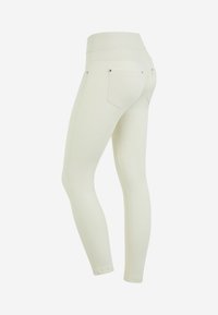 Leggings bianchi, realizzati in un tessuto elasticizzato, con un alto punto vita, due tasche posteriori e una texture liscia. Le cuciture laterali scendono lungo le gambe.