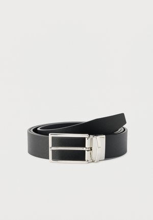 Ceinture en cuir noir enroulée avec une boucle rectangulaire argentée brillante sur un fond clair uni.