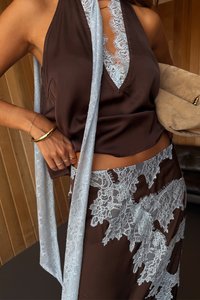 Õhuline pruun satiinist halter-top pitsäärtega ja sobiv seelik, millel on sinised pitsaktsendid. Üksne tekstuur, struktureeritud disain.