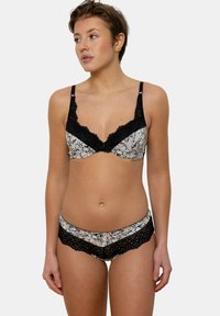 Ensemble soutien-gorge et culotte avec une finition en dentelle noire, motif floral beige et noir, avec des bretelles réglables et un design de culotte taille basse.