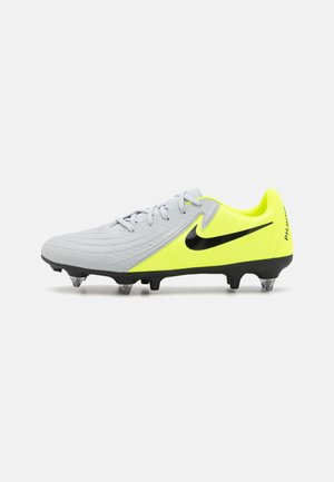 Nike futbola apavi ar pelēku augšdaļu ar strukturētu detaļām, neona dzelteniem akcentiem, melnu simbolu un caurspīdīgiem studiem saķerei.