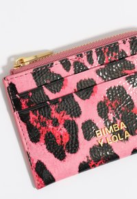Tarjetero de estampado de leopardo en rosa y negro con textura brillante, herrajes dorados y cuatro ranuras para tarjetas. Presenta el logo "BIMBA Y LOLA."