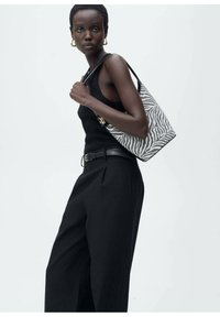 Borsa a mano con motivo a righe zebra in bianco e nero, dalla forma strutturata, con dettagli in oro e una tracolla in pelle nera.