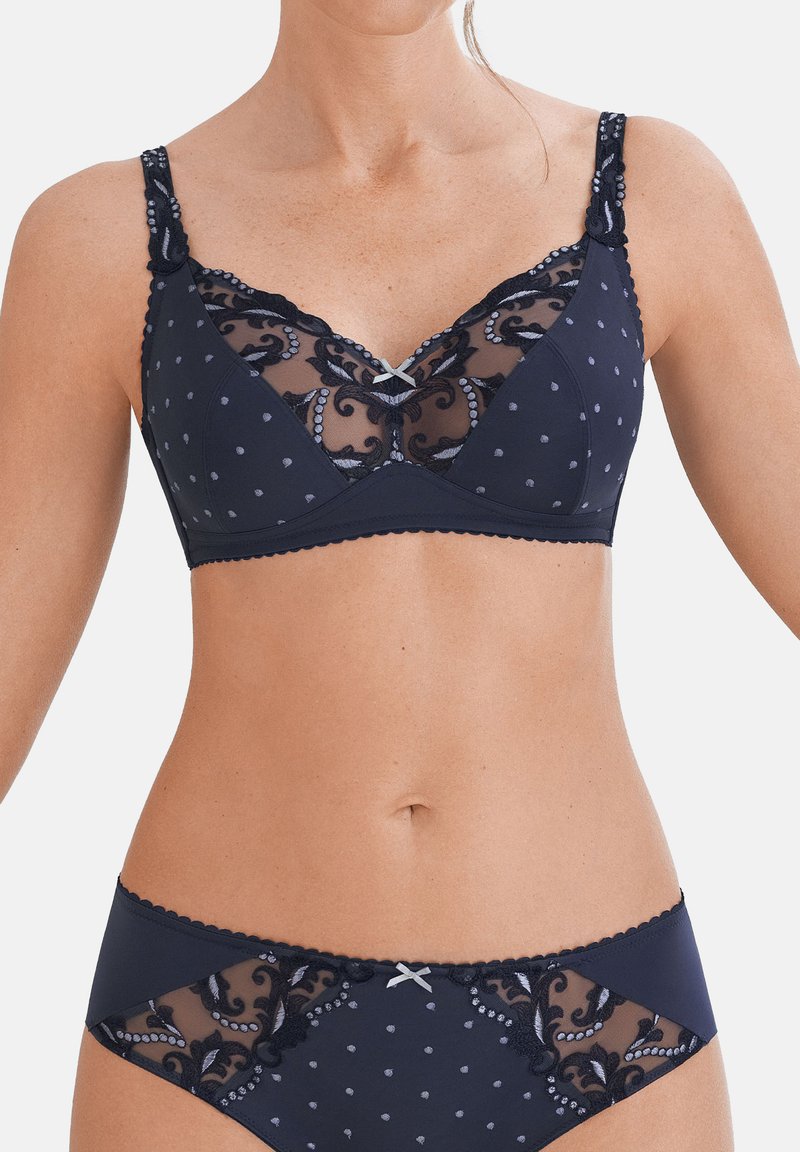 Reggiseno blu navy con rete trasparente e motivi a pois, ricami floreali, spalline regolabili e bordi ondulati. Presenta un piccolo dettaglio a fiocco.