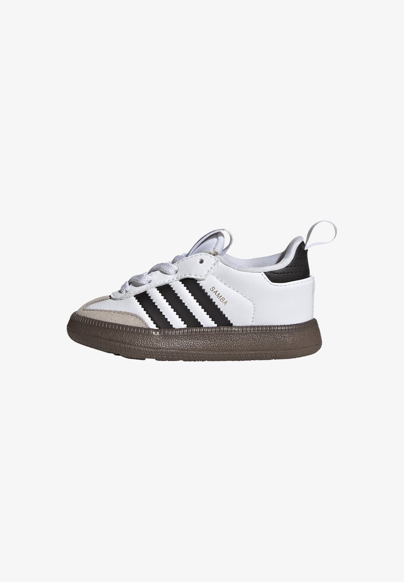 Baskets Adidas Samba blanches et noires avec semelle marron, languette noire au talon, ouverture à lacets à l'avant, et texte "SAMBA" sur la face latérale.
