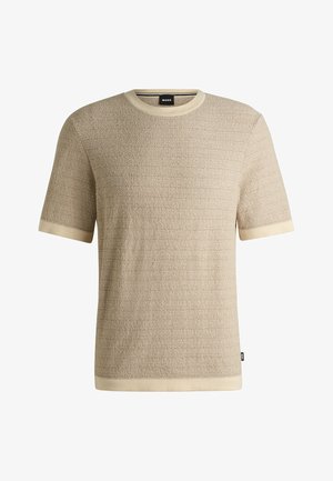 T-shirt beige a maniche corte con texture e un sottile motivo a righe, colletto e bordi delle maniche in crema a coste. Etichetta del marchio visibile.