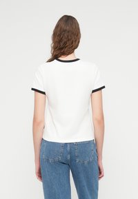 Λευκό μπλουζάκι με κοντά μανίκια, με μαύρη rib ύφανση στο γιακά και στα μανίκια, με απλό σχεδιασμό και άνετη εφαρμογή.