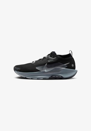 La chaussure Nike Trail ATC noire présente une tige en mesh respirant, une étiquette Gore-Tex, des accents réfléchissants et une semelle grise rembourrée avec une adhérence texturée.
