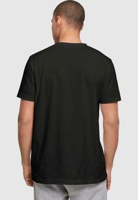 Black cotton t-shirt with short sleeves, crew neck, and a smooth texture. No visible logos or patterns on the back.