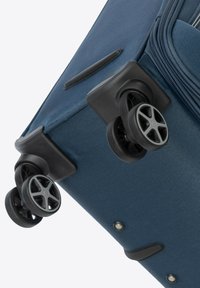Valigia blu in tessuto con superficie testurizzata, dotata di quattro ruote nere, maniglie laterali e dettagli in zip.